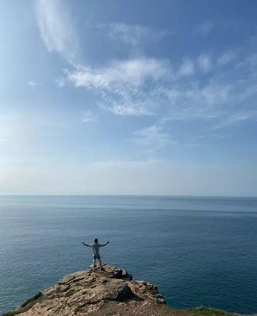 Andrew on a cliff overlooking the sea on a hike in Cornwall